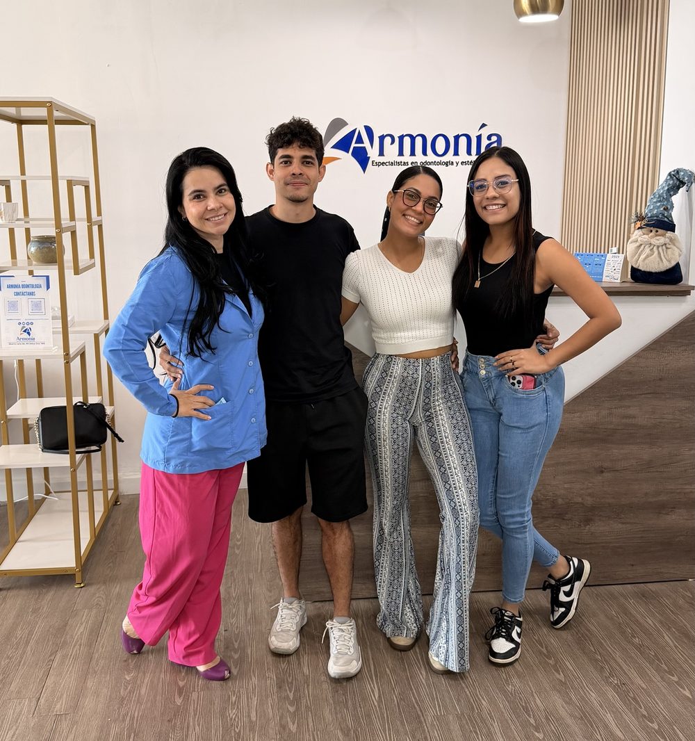 El equipo de Armonía sonriendo frente al logo en la recepción