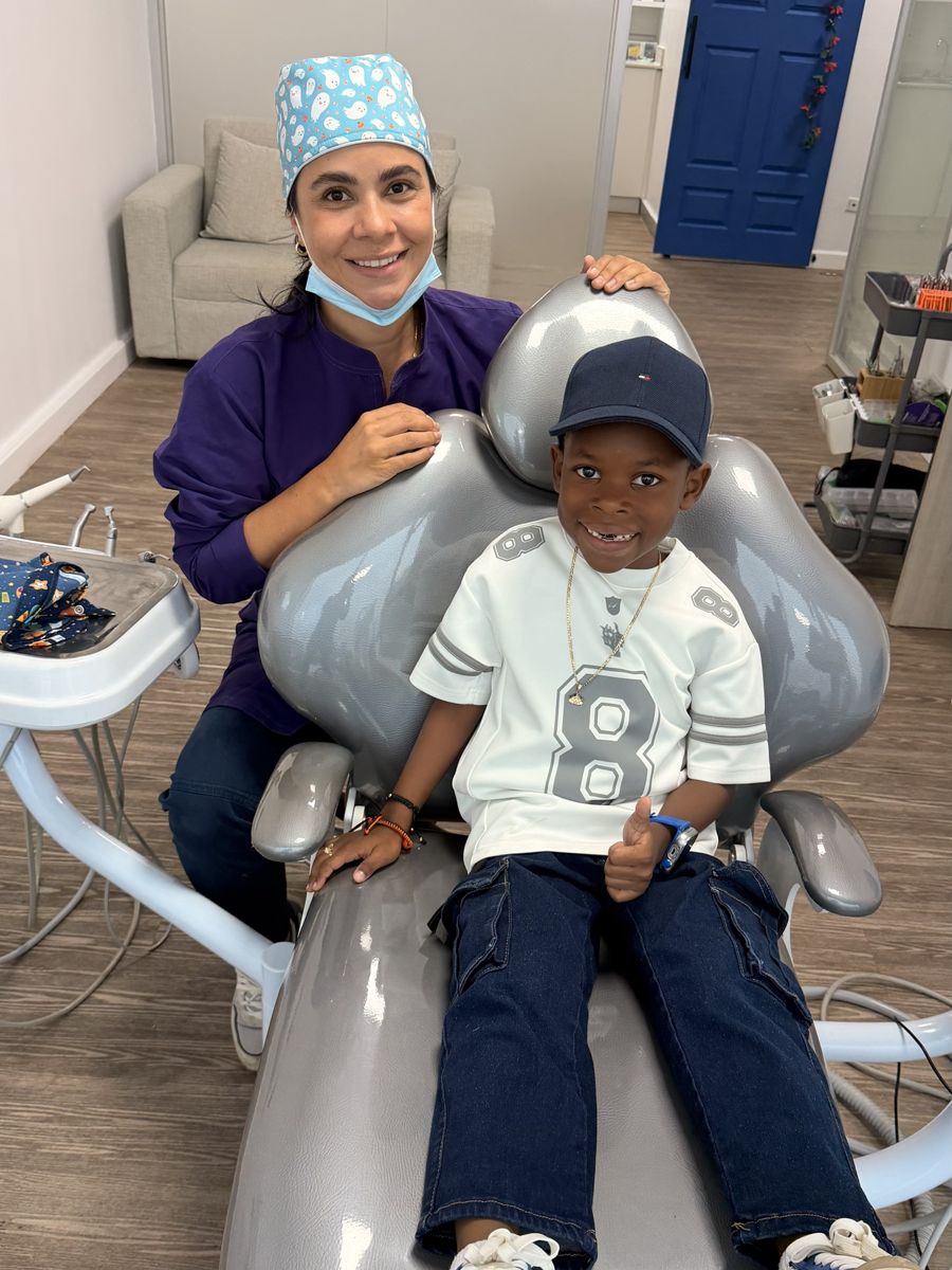 Niño sonriendo en el sillón dental junto a su odontóloga